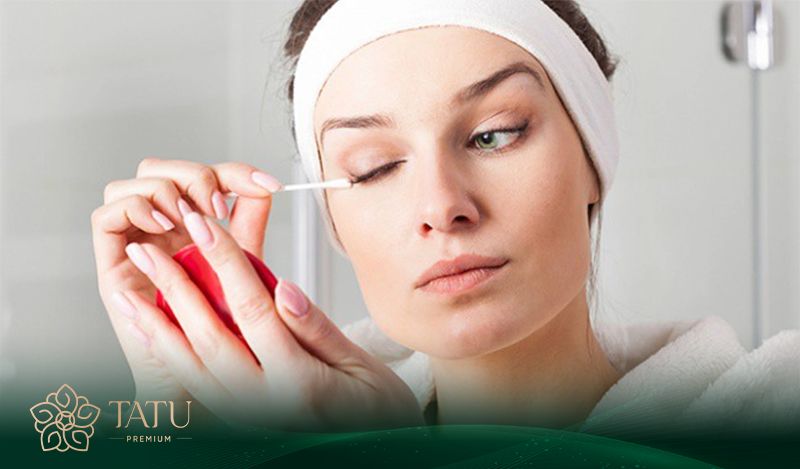 Sử dụng tăm bông sạch và dung dịch muối loãng để vệ sinh nhẹ nhàng vùng da quanh mắt.